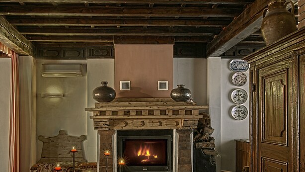 A traditional room with a fireplace, patterned rug, and wooden furniture. - Villa Belfiore (Ostellato)