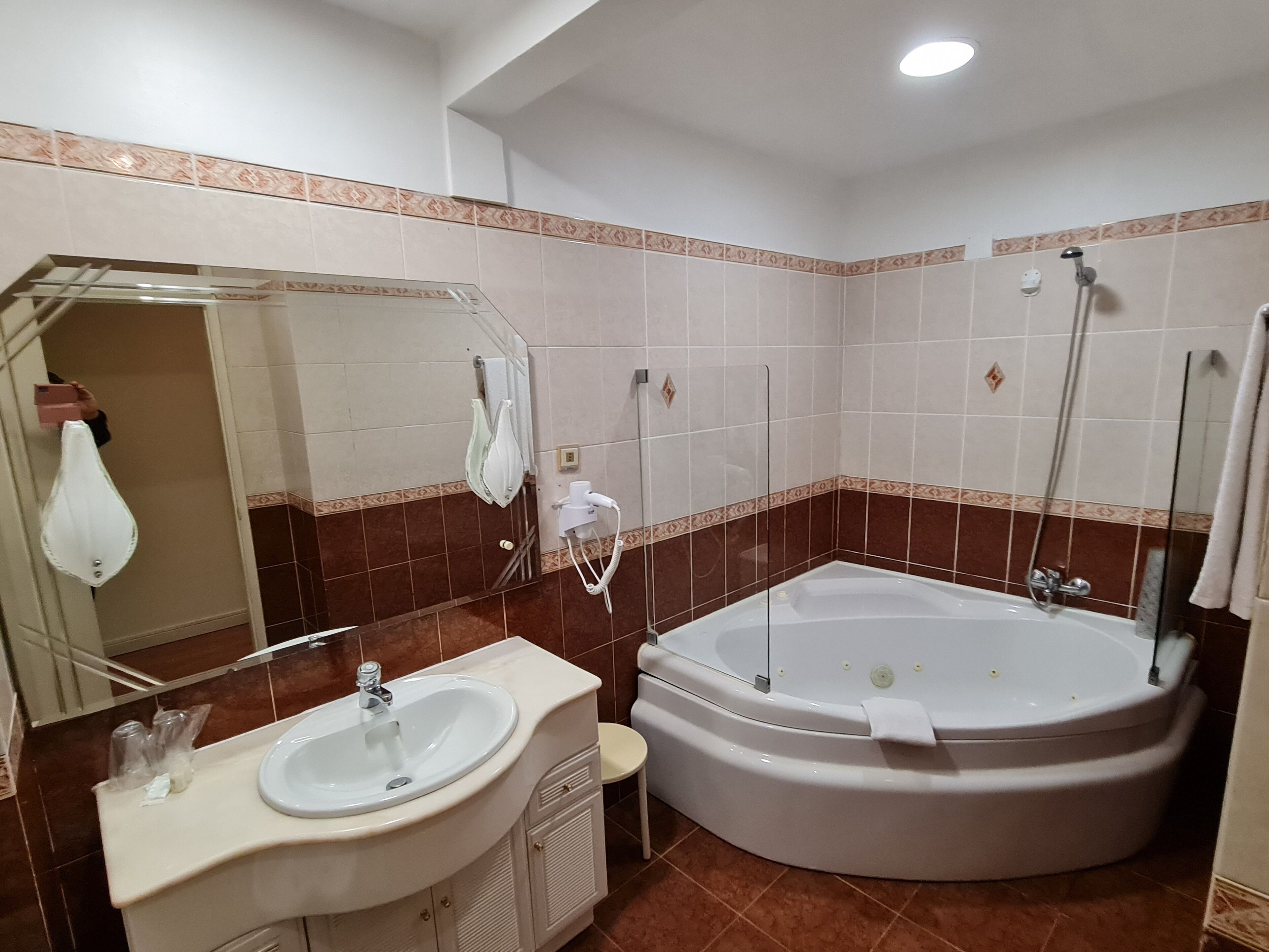 Casa de banho com lavatório, espelho, chuveiro e banheira.