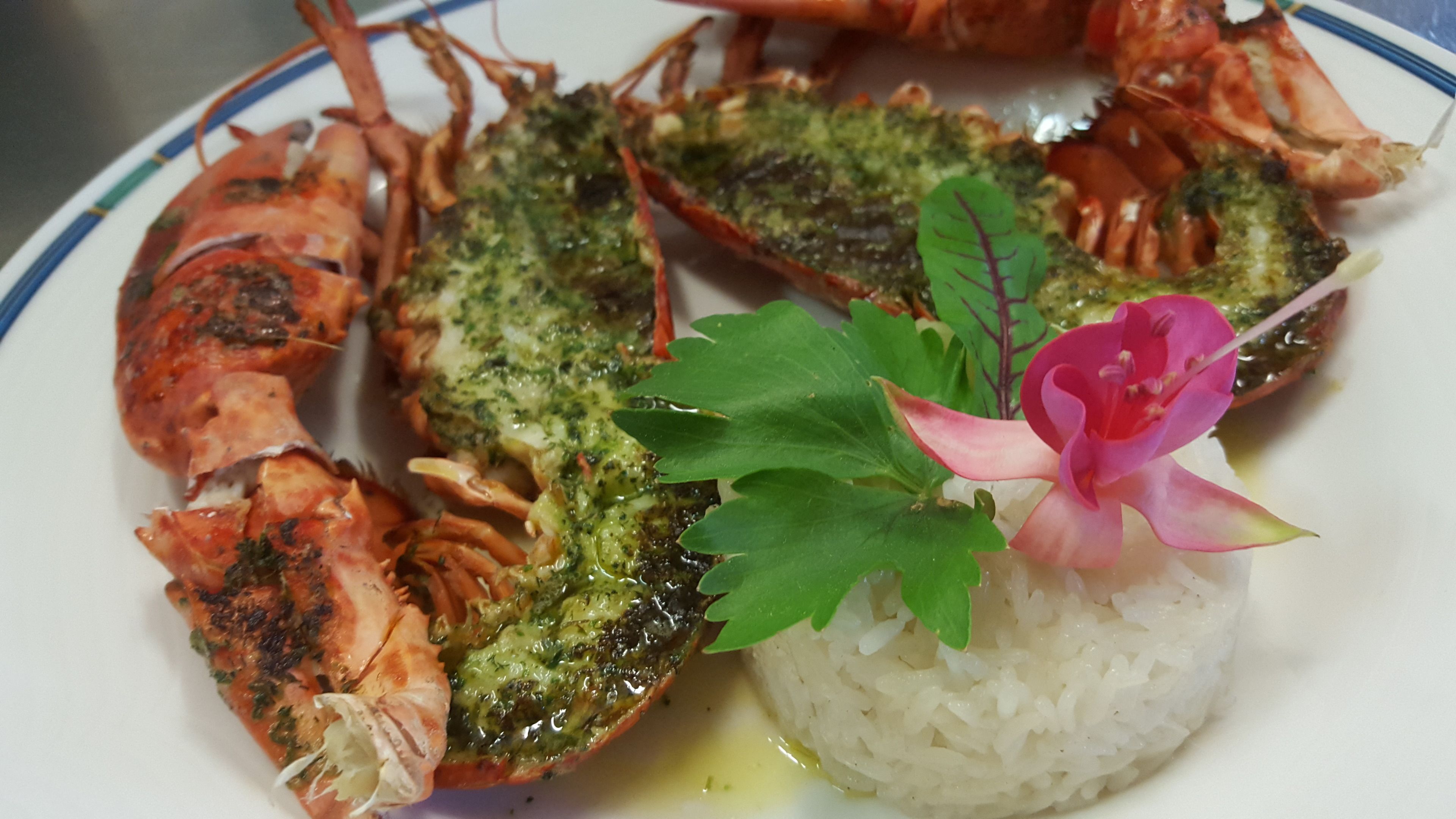 Une assiette contenant des fruits de mer cuits, du riz et une fleur décorative.