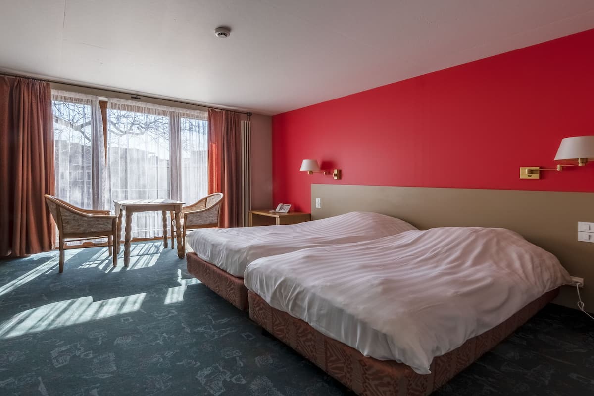A hotel room with two beds, a desk, and a chair.