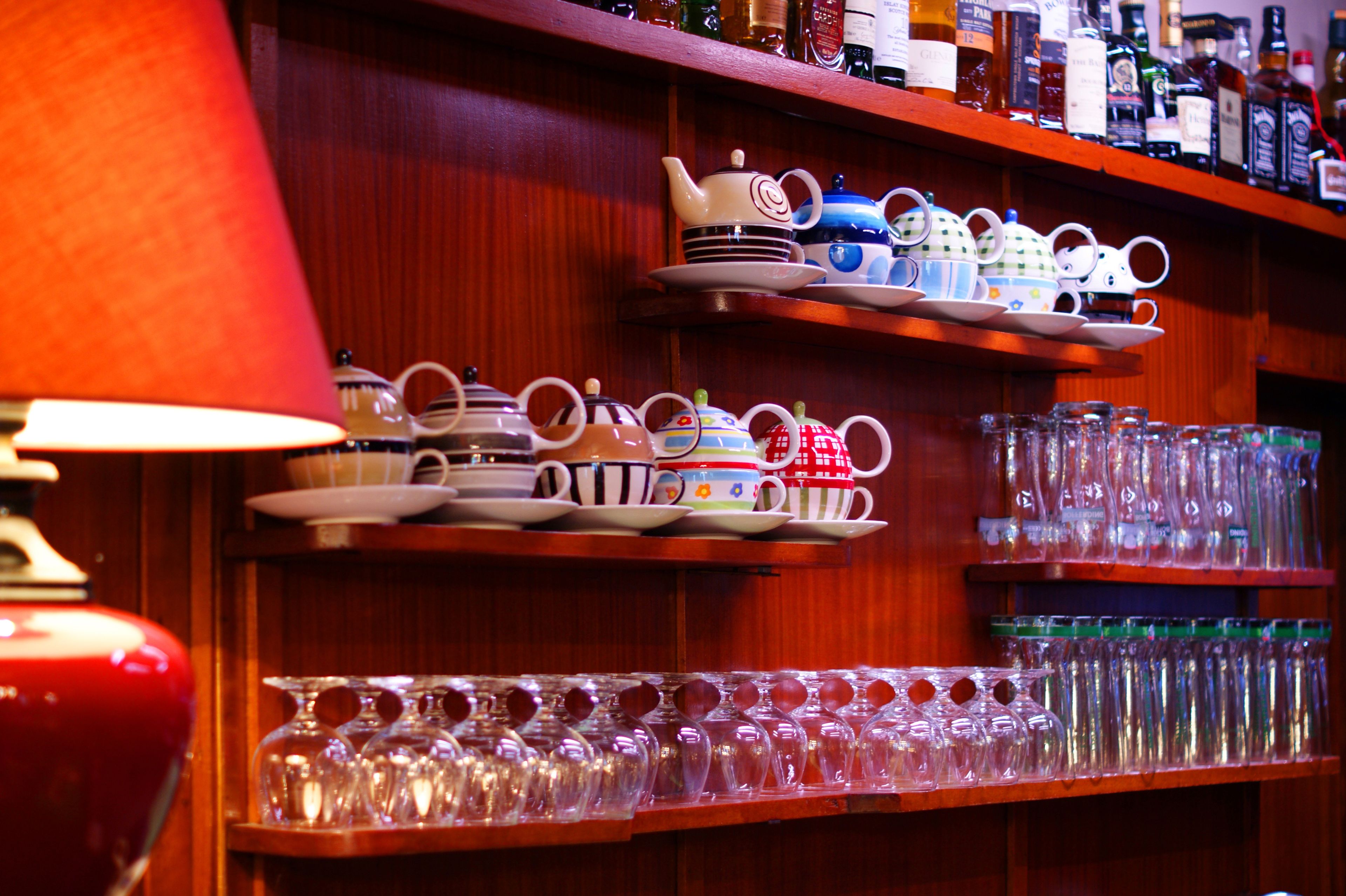 Shelves with various teapots and cups, and a row of glasses.