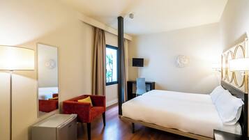 Een hotelkamer met een bed, bureau, stoel, spiegel en televisie.