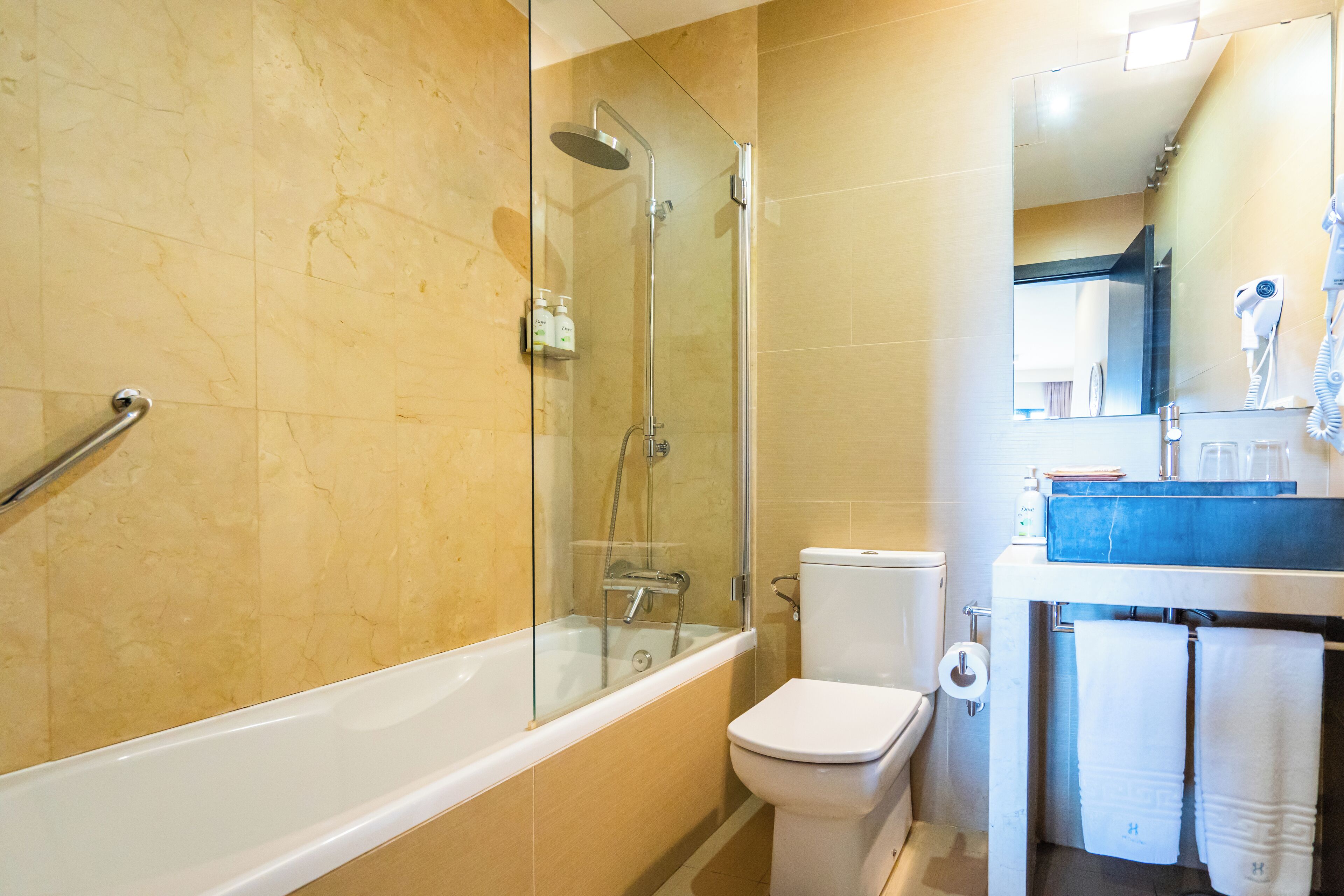 Een badkamer met een douche met glazen wand, een wit toilet en een wastafel met een blauw aanrechtblad.