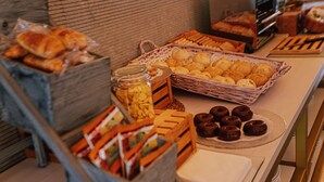 Una mesa de buffet con diversos alimentos, incluyendo pasteles, pan y rosquillas.