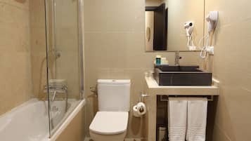 A modern bathroom with a glass-enclosed shower, a white toilet, a black sink, and a mirror above the sink.