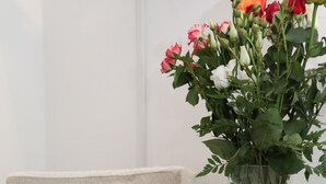 Un tavolo con un'elegante composizione floreale, una bottiglia e un piatto con fragole.