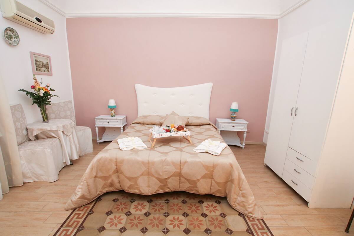 Una camera da letto ordinata con un letto, comodini, un armadio e un tappeto decorativo.