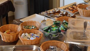 A buffet setup with various food items, including ham, pastries, and beverages. - Hôtel du Parc Even (Malakoff)