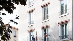 A building with multiple balconies, a flag, and a sign indicating a hotel. - Hôtel du Parc Even (Malakoff)