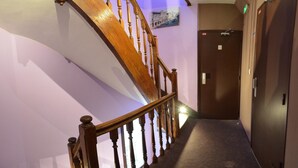 A wooden staircase with a handrail leading to a door with a number plate. - Hôtel du Parc Even (Malakoff)