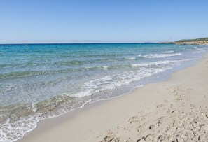 A beach with clear blue water and a sandy shore.