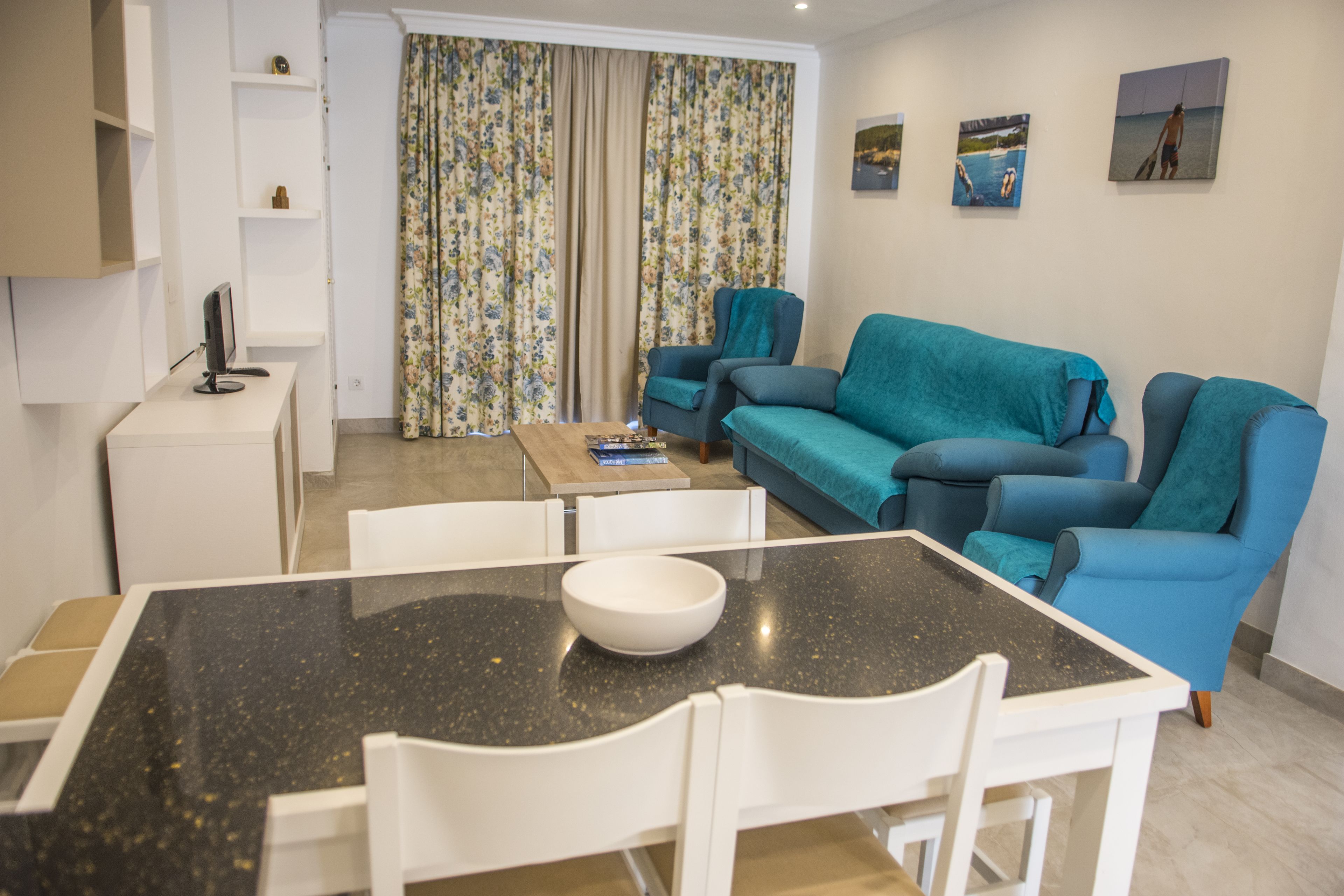 A modern living room with a dining table, a sofa, and a TV on a stand.