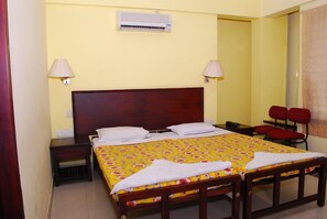Una habitación de hotel con una cama, dos lámparas de noche, un teléfono, una mesita y un espejo.
