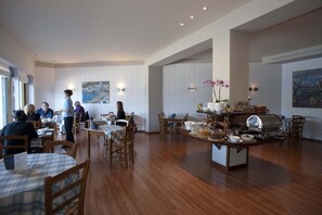A spacious dining area with wooden tables and chairs, a central island with a grill, and artwork on the walls.