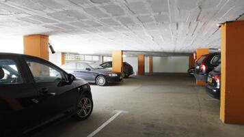 A parking garage with concrete pillars and cars parked.
