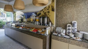 A buffet setup with various food items, a coffee station, and a selection of plates and cups. - Hotel Anassa (Santorini)
