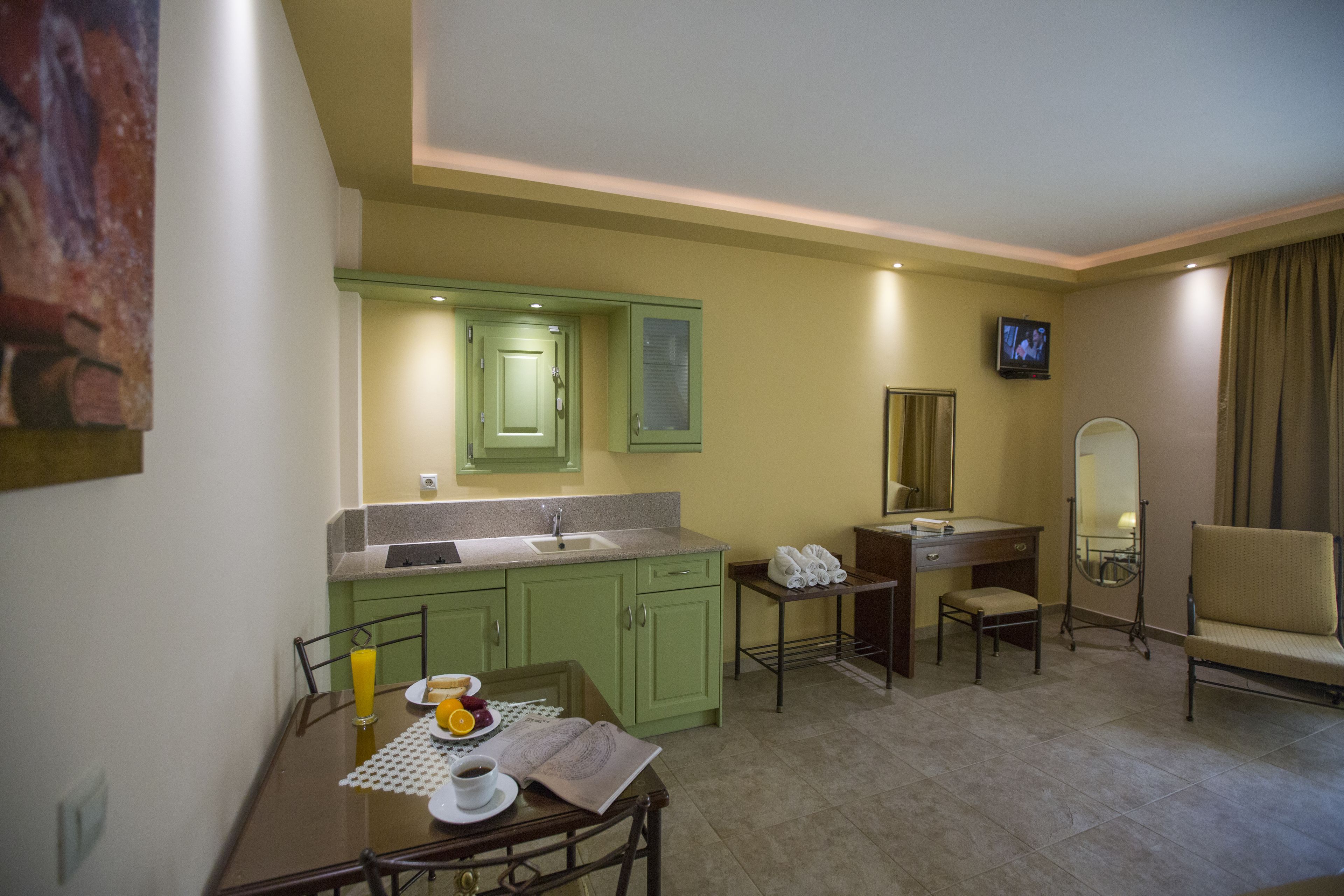 A hotel room with a dining table set with breakfast, a small TV, a mirror, and a chair.