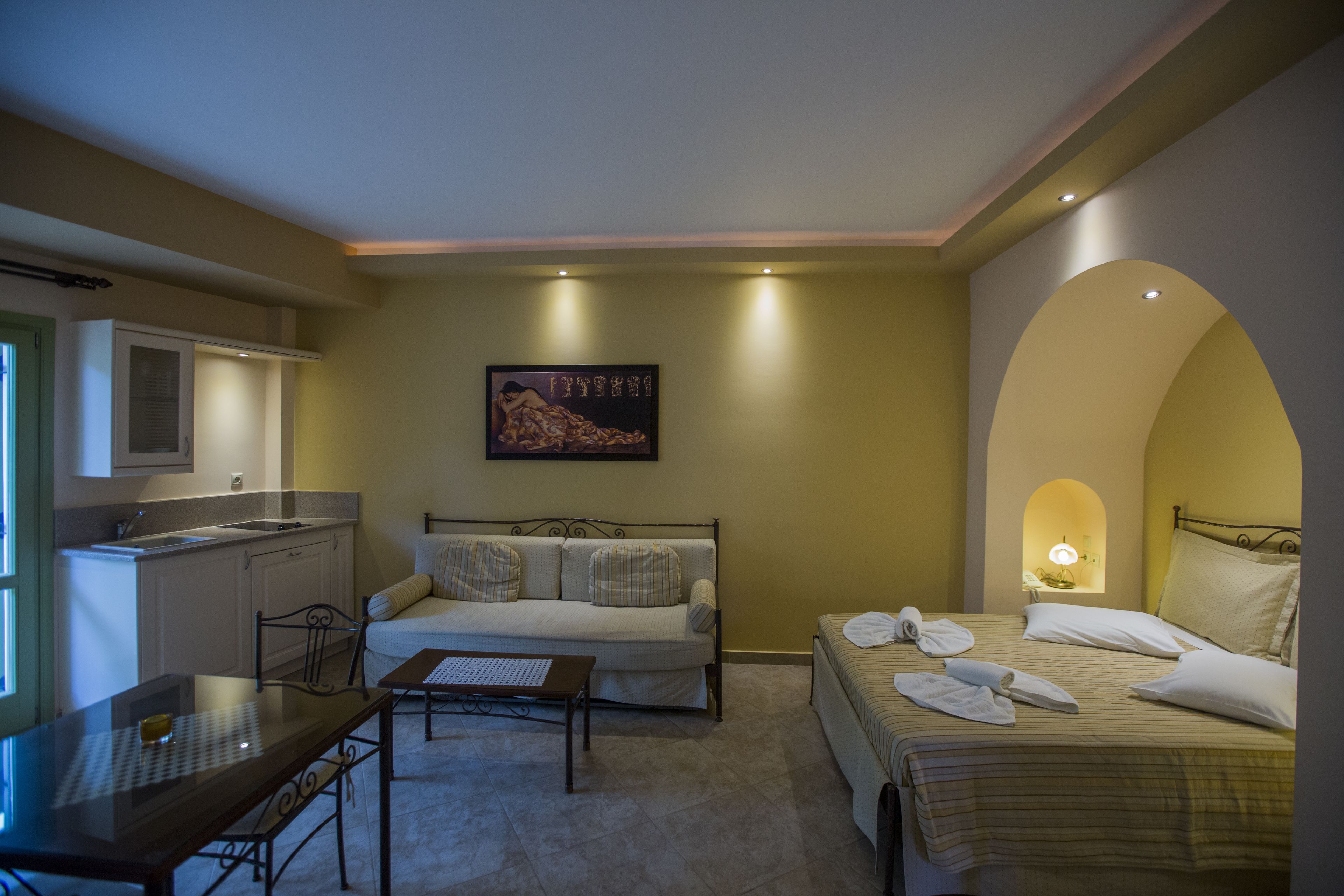Una habitación de hotel con cama, sofá, mesa de comedor y zona de cocina.