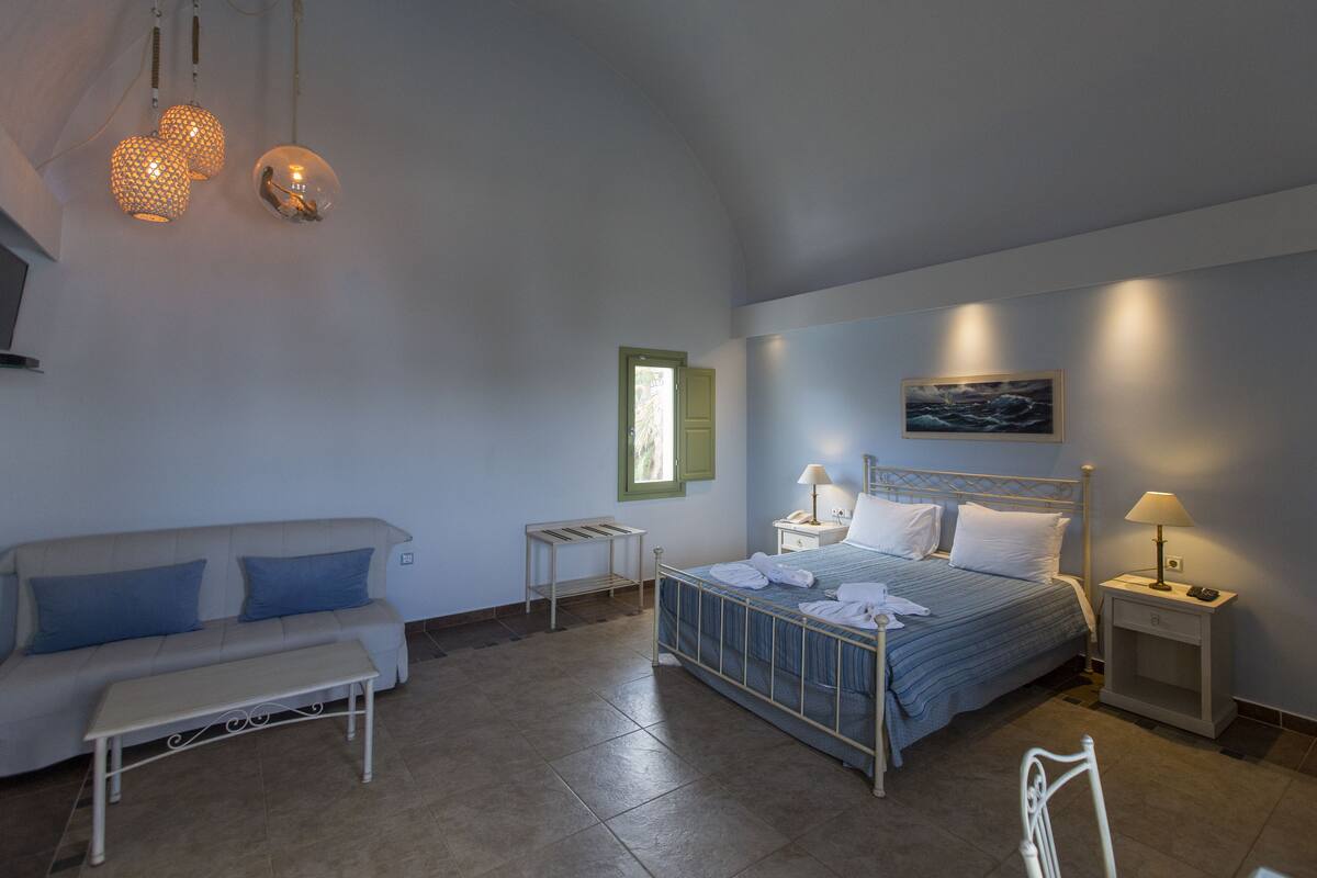 A bedroom with a bed, bedside tables, a nightstand, a bench, and hanging lamps.