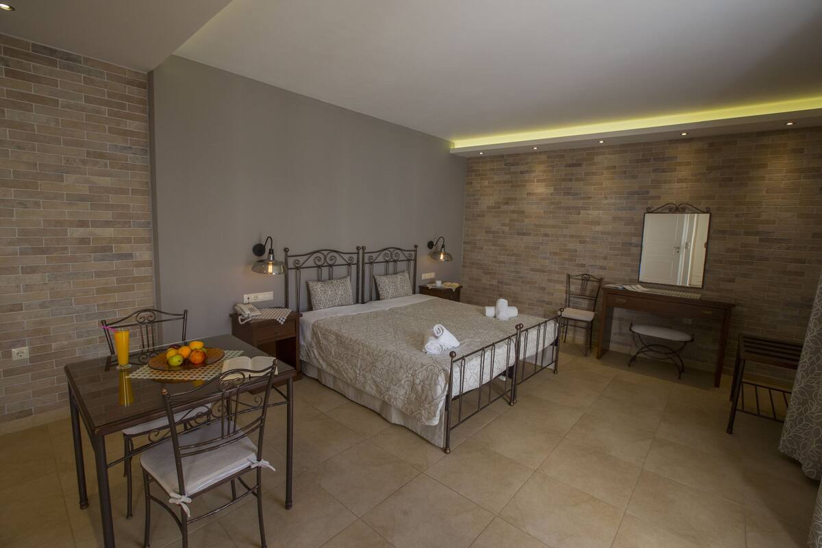 A hotel room with a bed, bedside tables, a desk, a chair, and a dining table with chairs.