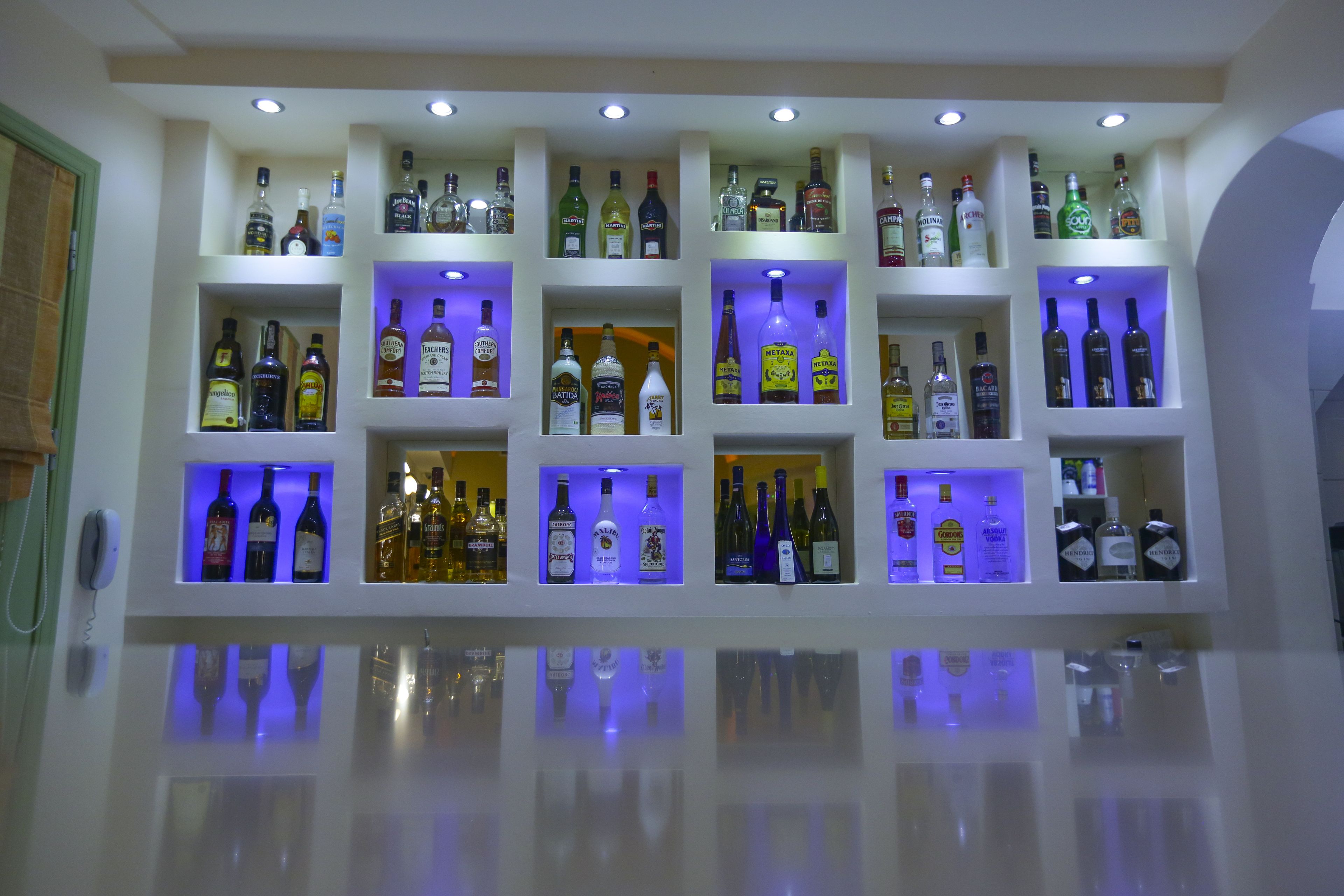 A wall of liquor bottles organized in shelves with illuminated sections.
