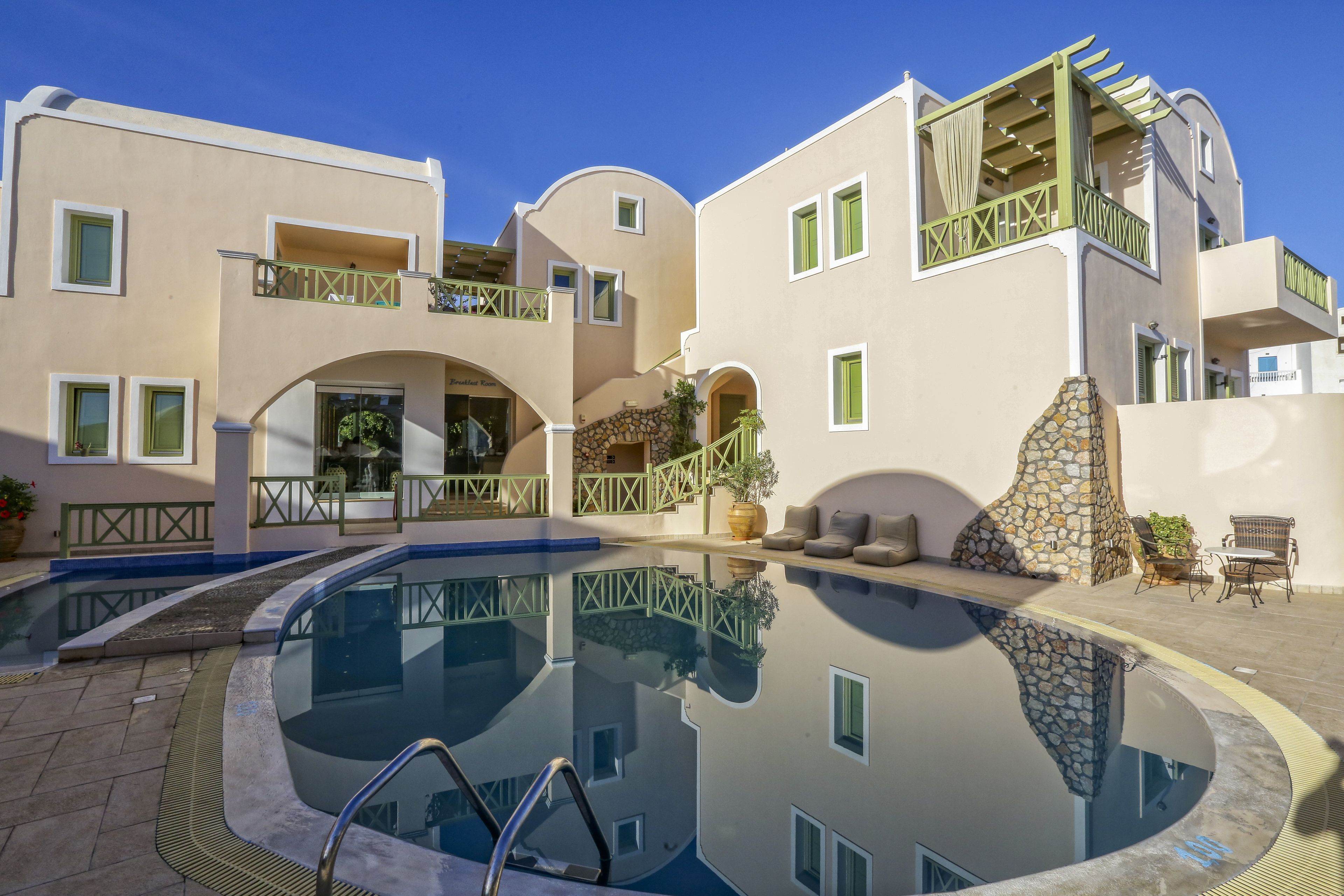 Un edificio moderno con piscina, zona de estar exterior y un elemento decorativo de piedra.