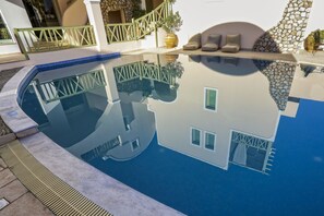 Una piscina al aire libre, sombrillas, sillones reclinables de piscina