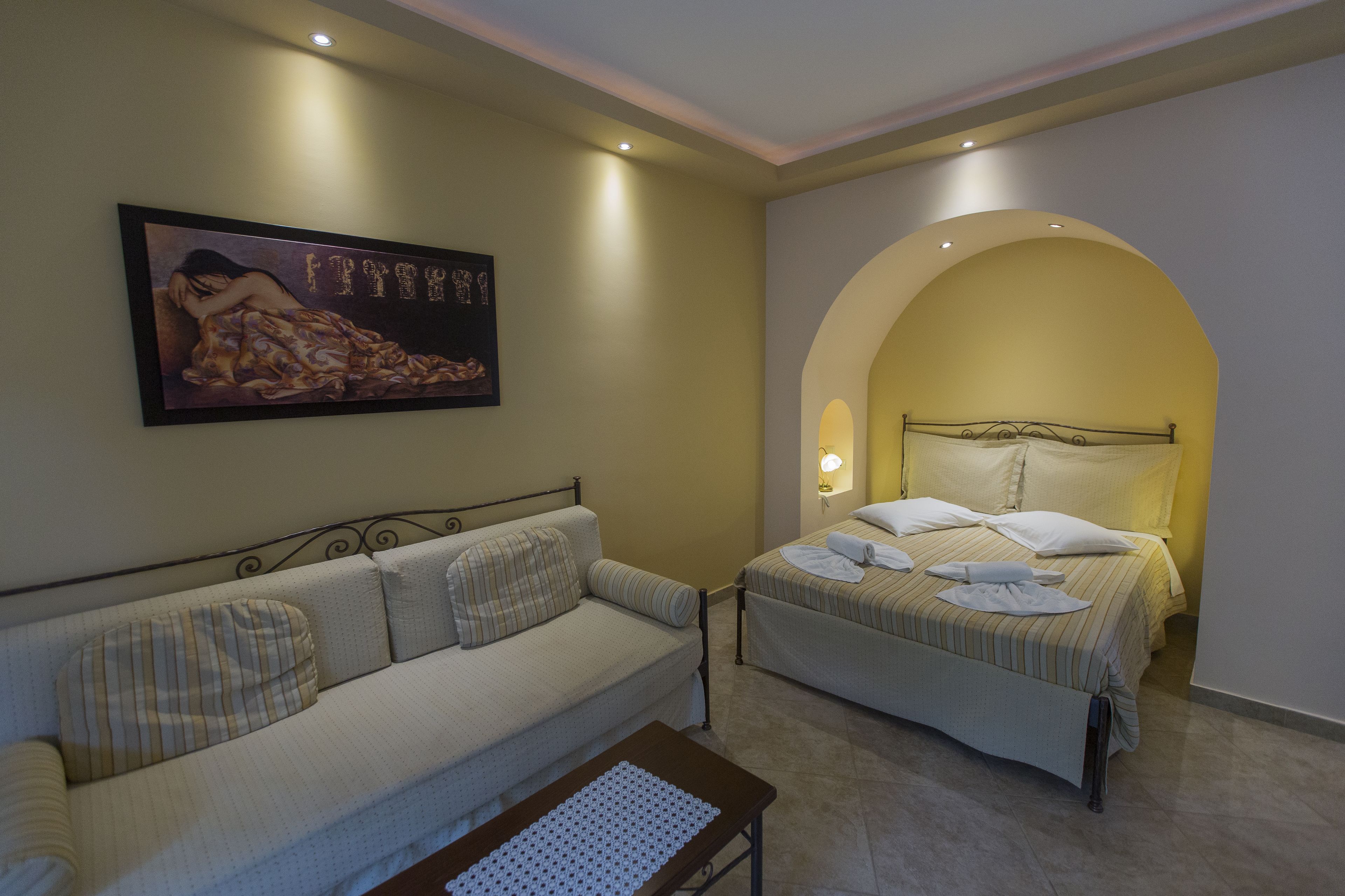 A hotel room with a sofa, a bed, and a painting on the wall.