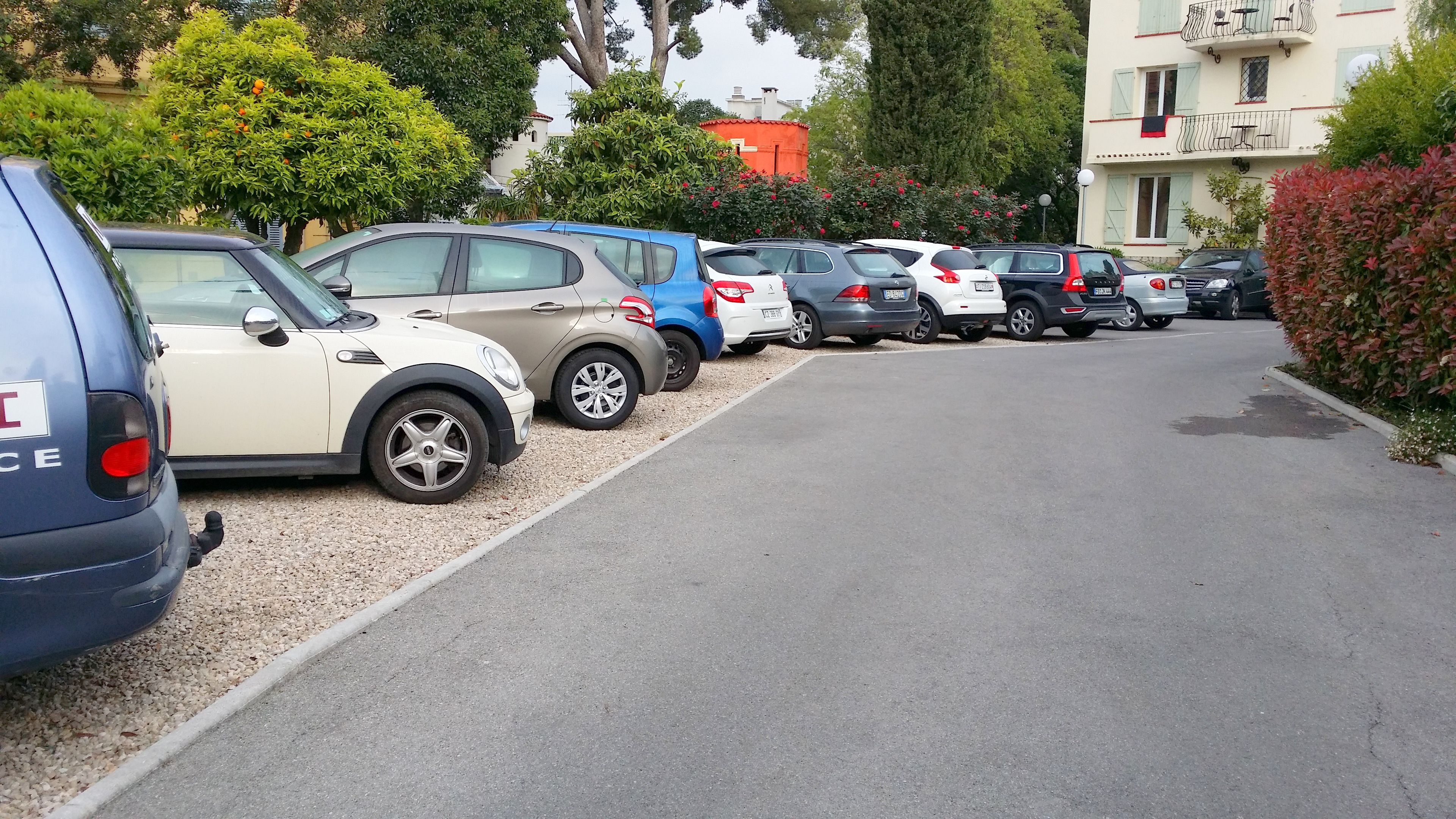 A row of parked cars along a street with buildings in the background.