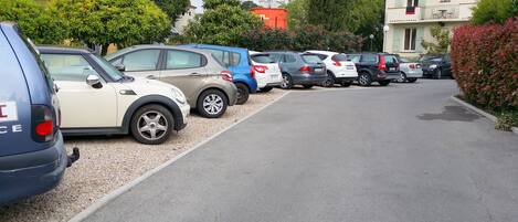 A row of parked cars along a street with buildings in the background.