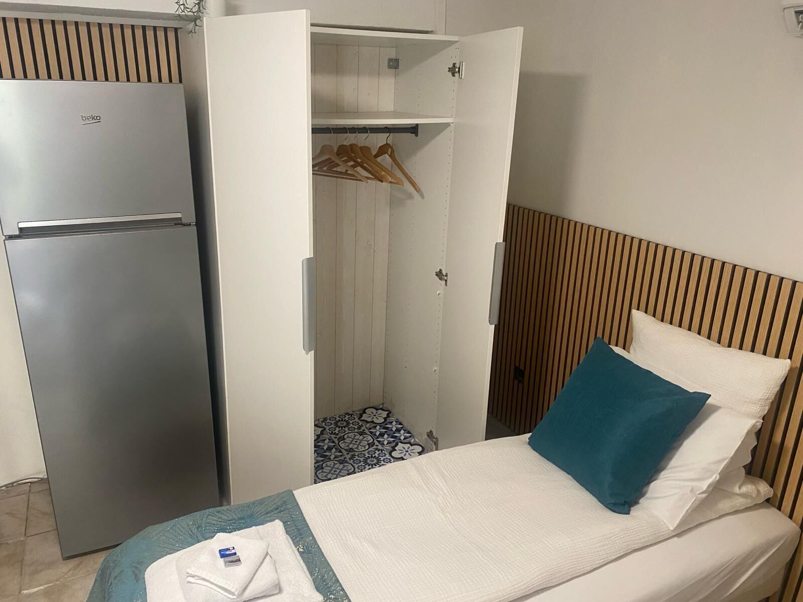 Habitación de hotel pequeña con cama, armario y minibar.