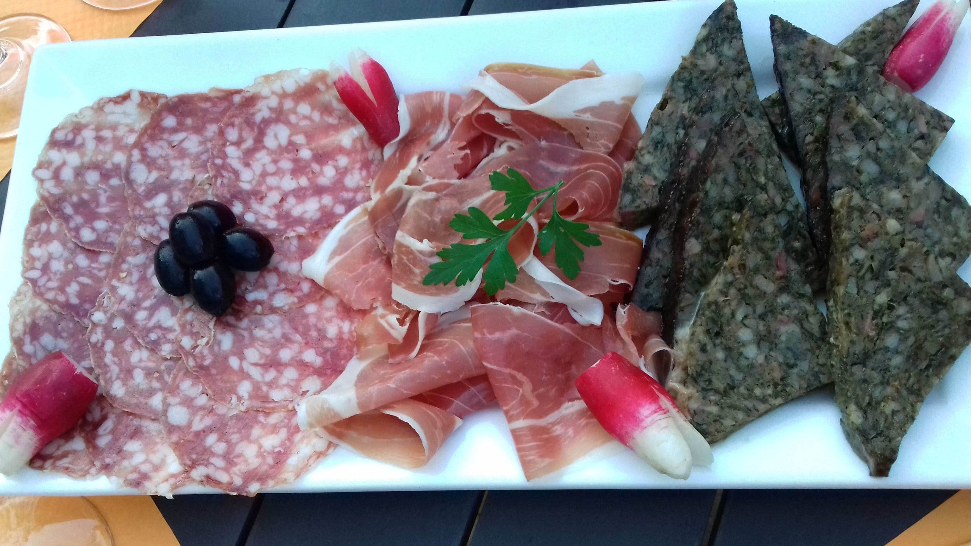 A charcuterie board with various meats and olives.
