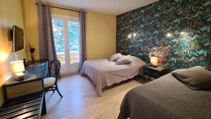 Une chambre à coucher avec un lit, un bureau avec une lampe, une chaise et une vue à travers une porte vitrée.