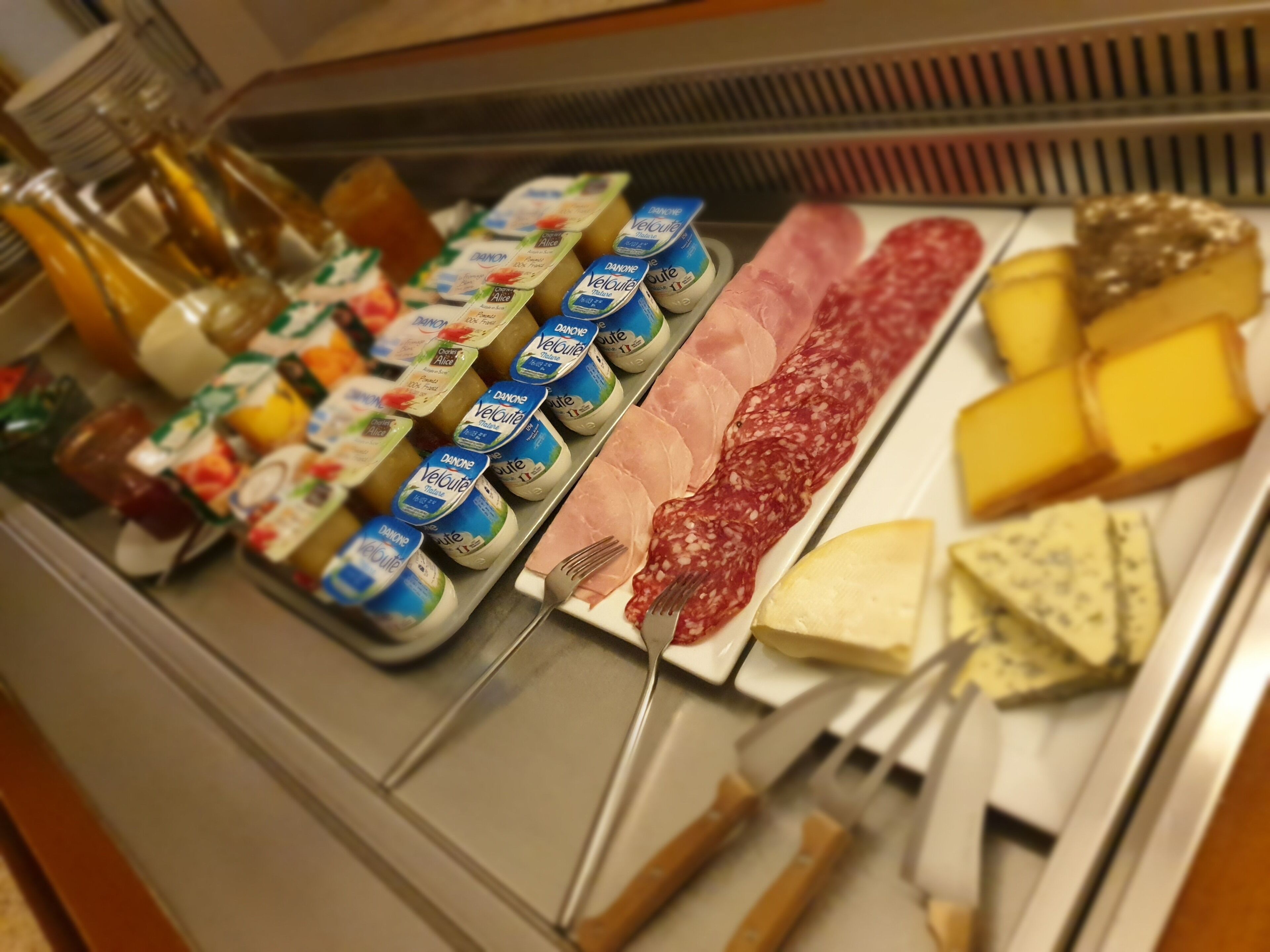 A deli counter with various cheeses, meats, and condiments.