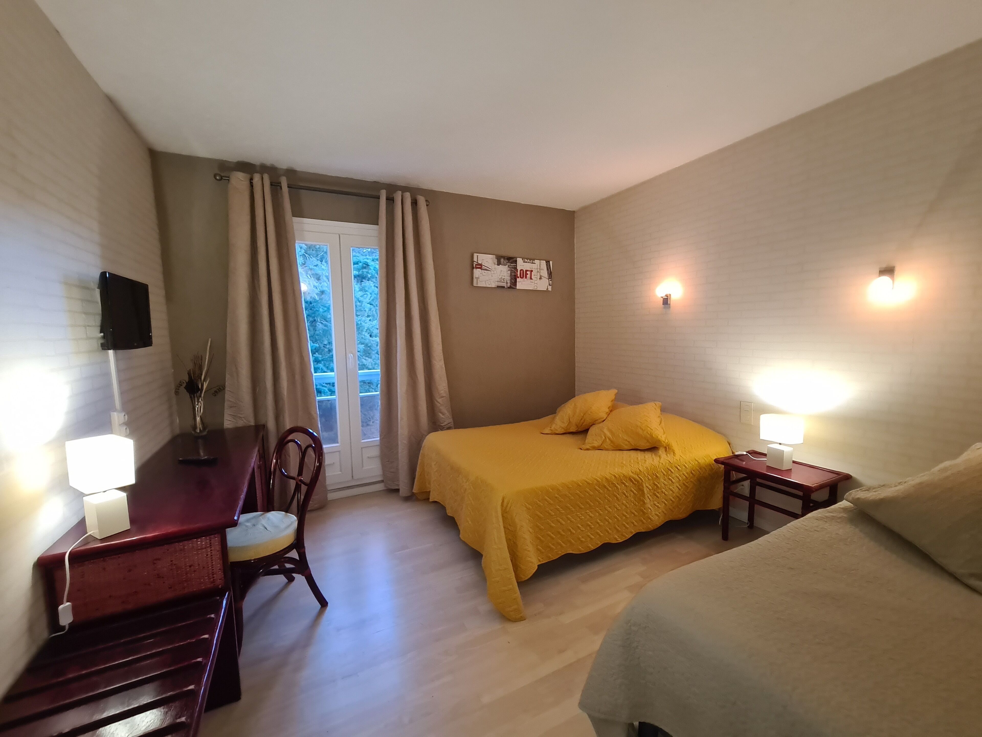 Una habitación con cama, escritorio, silla y ventana con cortinas.