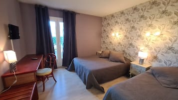A hotel room with two beds, a desk, a chair, and a TV.