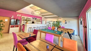 Un espace bar équipé d’une table de billard et de queues de billard, d’une table de snooker et d’un bar bien approvisionné en bouteilles de différentes sortes.
