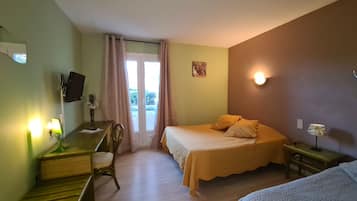 Een hotelkamer met een bed, een bureau met stoel, een aan de muur bevestigde televisie en een raam met gordijnen.