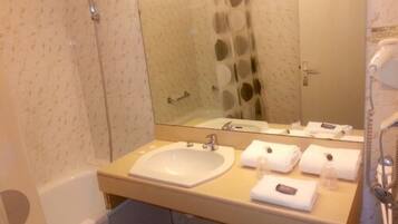 Un baño con bañera, lavamanos, espejo y toallero.