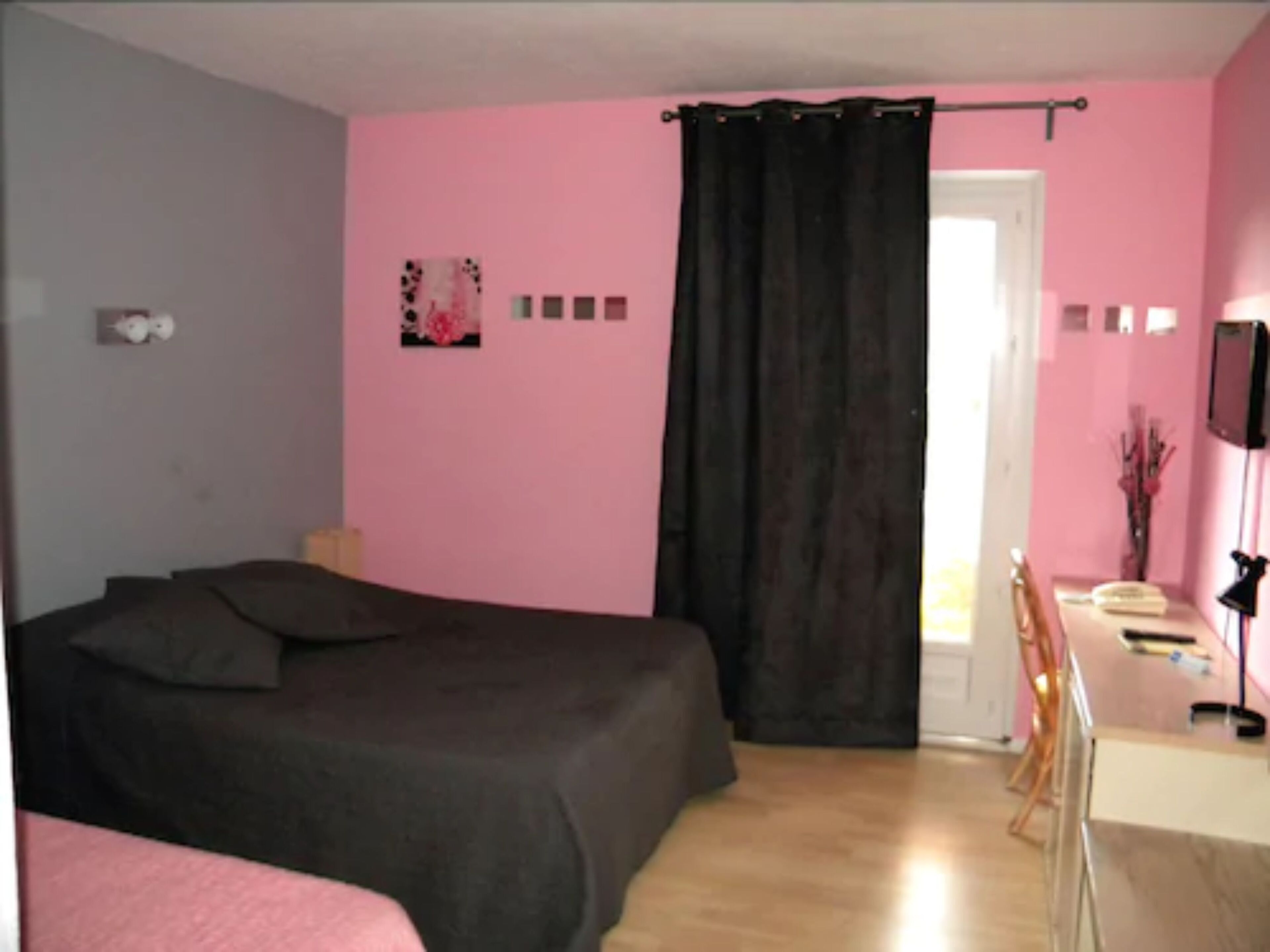 A bedroom with a bed, a desk, and a chair.