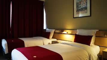 Una habitación de hotel con dos camas, una mesita de noche y una lámpara fijada a la pared.