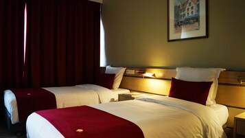 Una habitación de hotel con dos camas, una mesita de noche y una lámpara fijada a la pared.