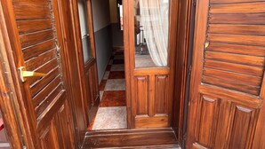 A wooden door with a glass panel and a curtain, leading into a hallway with a checkered floor. - Hostal Ruta de Lorca (Alfacar)
