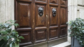 A set of wooden double doors with ornate metal knockers and a small step leading up to them. - La Maison dell'Orologio (Rome)