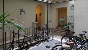 A courtyard with bicycles parked against a wall, a potted plant, and a staircase leading to an upper level. - La Maison dell'Orologio (Rome)