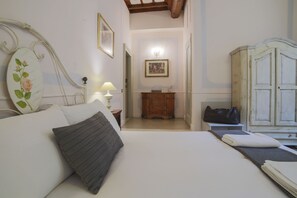 A bedroom with a bed, bedside table, lamp, wardrobe, and a hallway leading to a bathroom. - La Maison dell'Orologio (Rome)
