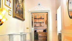 A hallway with a clear glass partition, a patterned floor, and a door leading to a room with a clock and shelves. - La Maison dell'Orologio (Rome)
