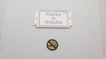 Un panneau indiquant « PIAZZA DI SPAGNA » avec un symbole interdisant de fumer en dessous.