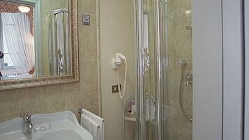 Un baño con lavamanos, espejo, ducha e inodoro.