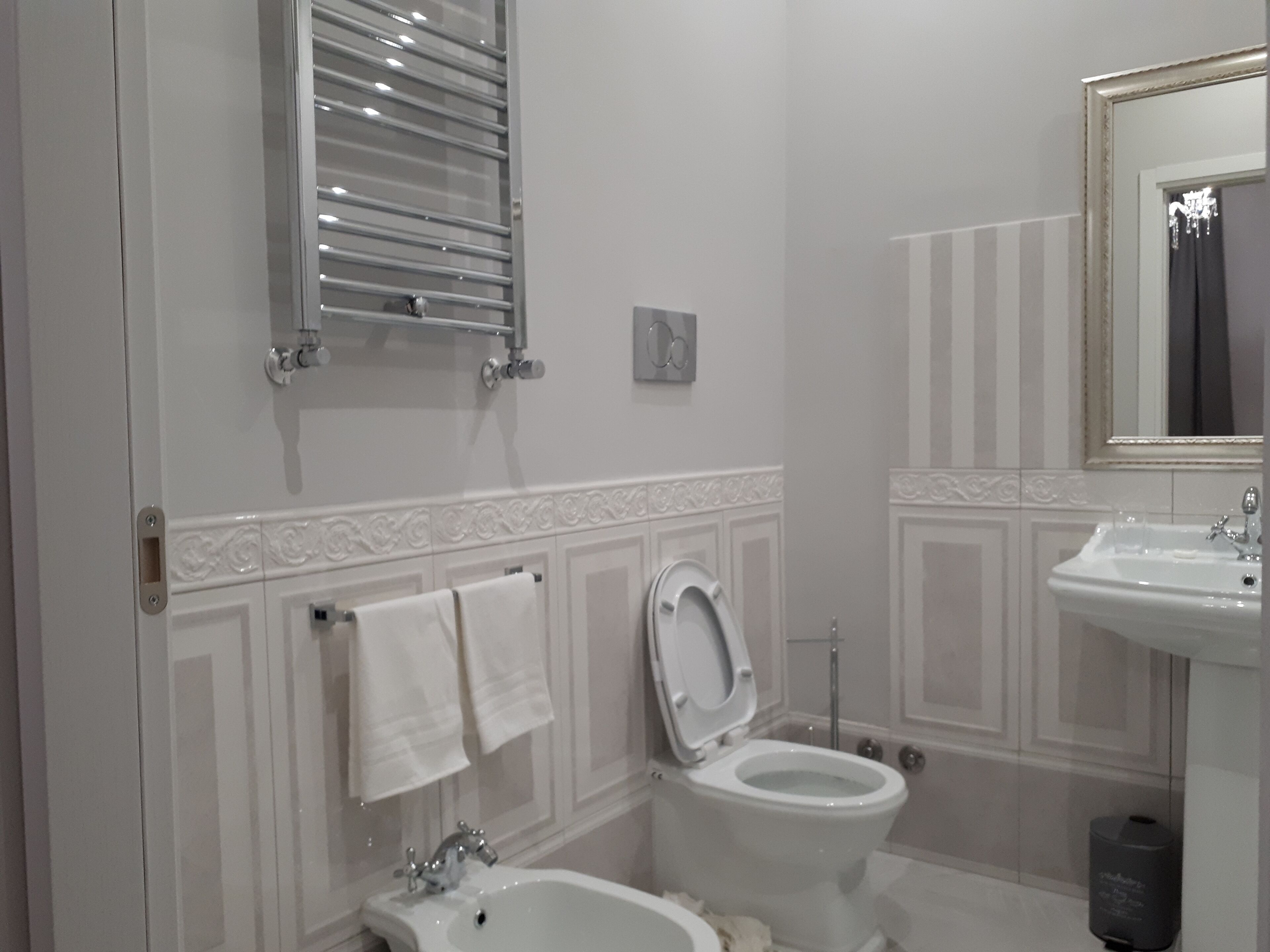 A bathroom with a toilet, bidet, sink, and towel rack.